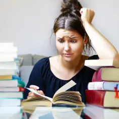 Zestresowana studentka z książkami, czuje się przytłoczona nauką, to objawy, które mogą wskazywać na nerwicę.